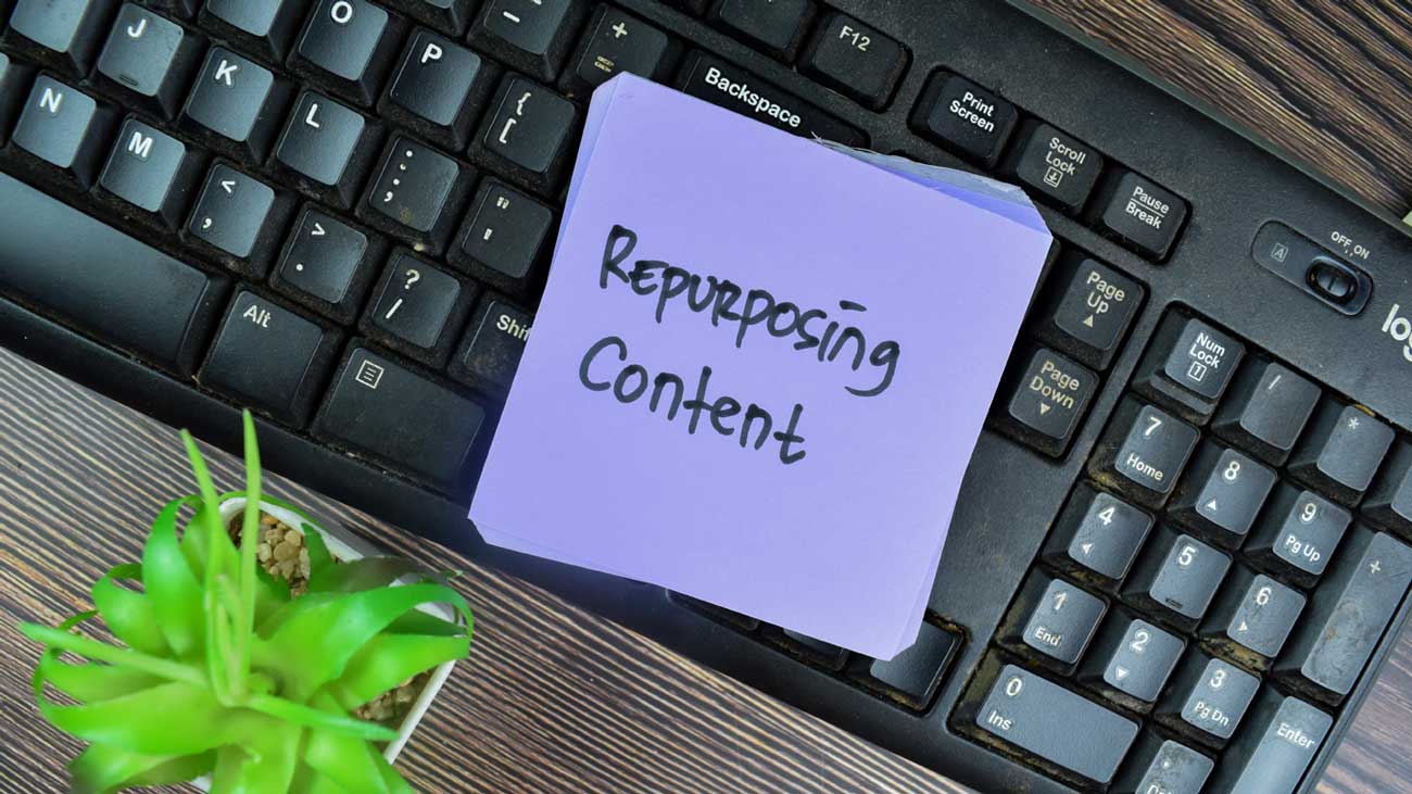 sticky note with the words repurpose content on keyboard.